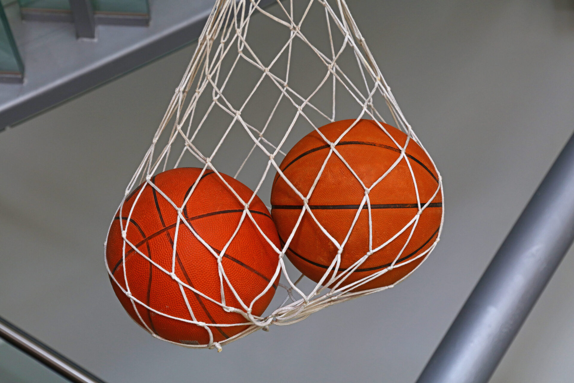 Close up two basketball balls hanging in mesh sack, low angle side view.